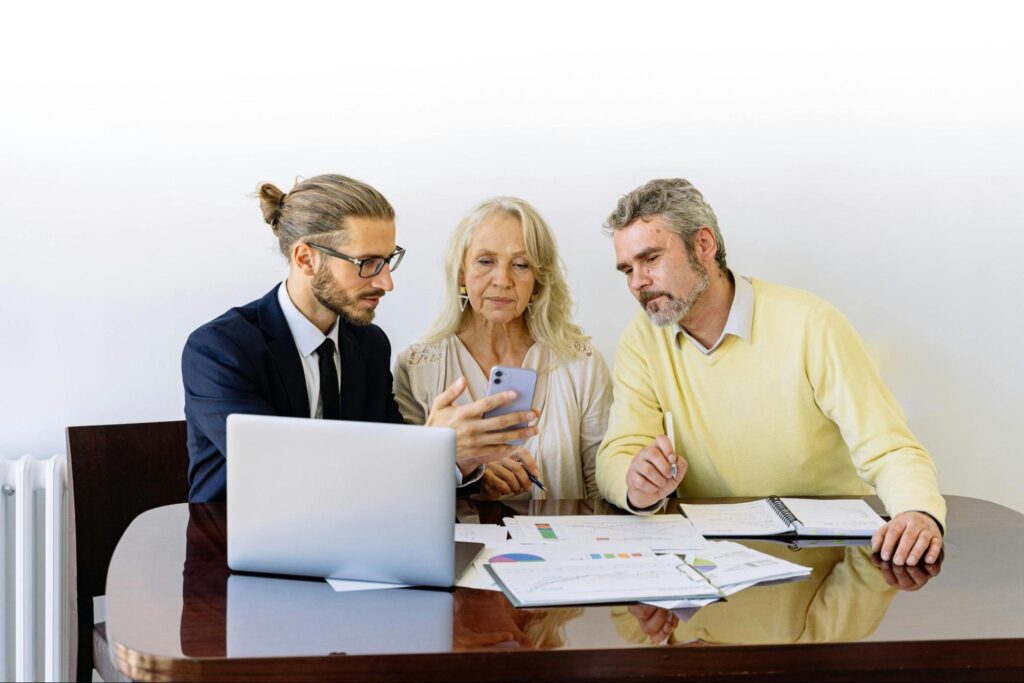 Couple talking to real estate agent looking at phone