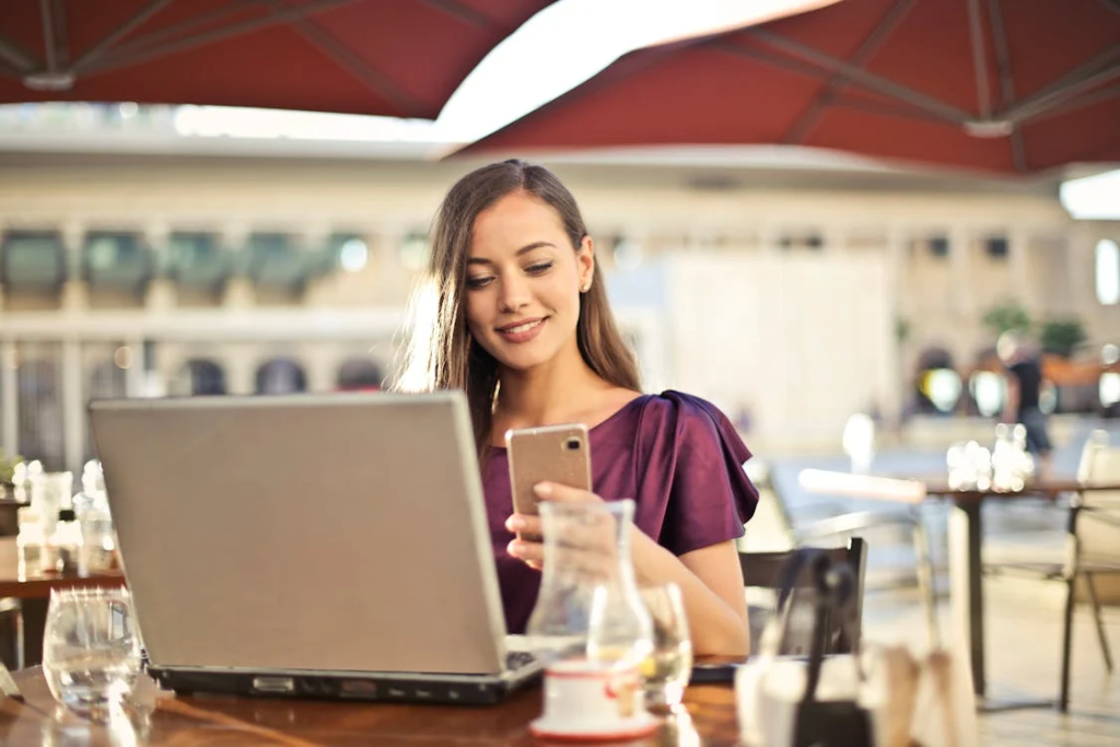 A woman using a smartphone and laptop
