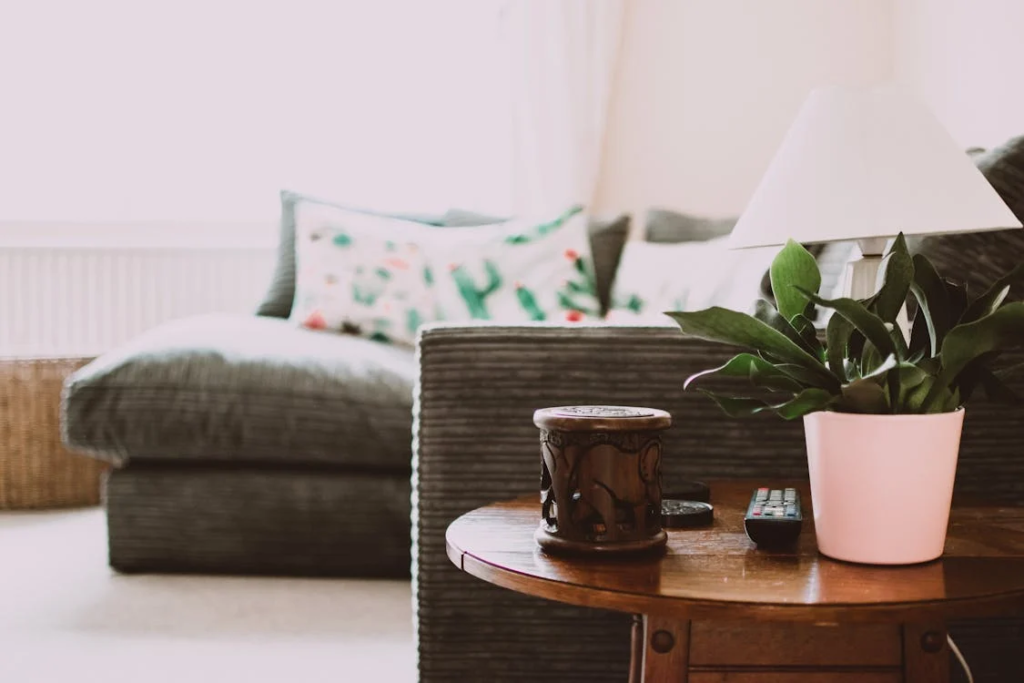 A cozy couch and a round wooden end table