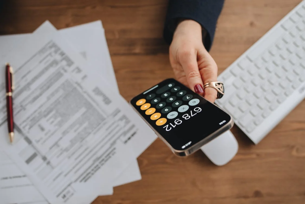 A woman with a calculator app open and papers