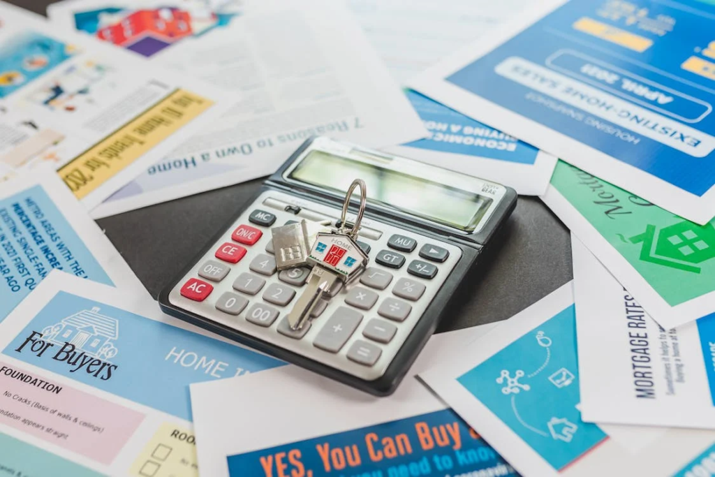 A black and gray calculator on a desk with house buying flyers