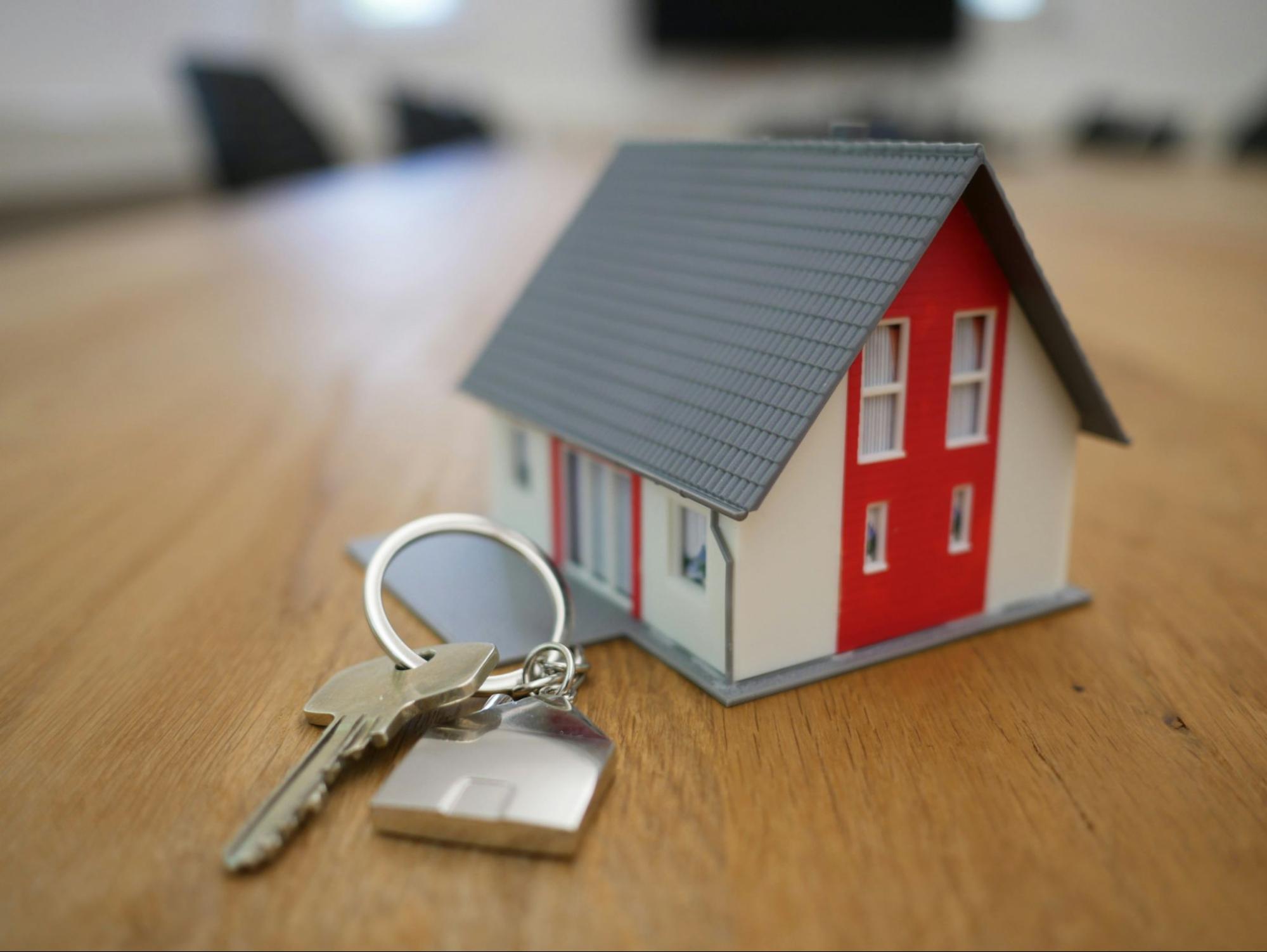 Keys on a table next to house figurine