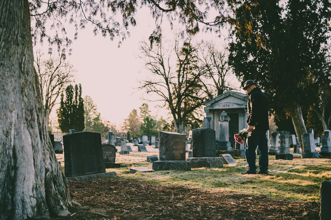 A man in a black jacket visiting a grave