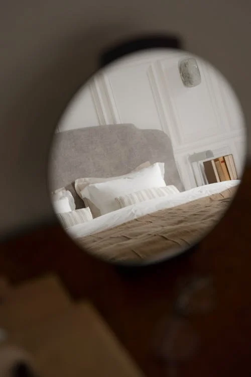 A bed reflected in a round mirror