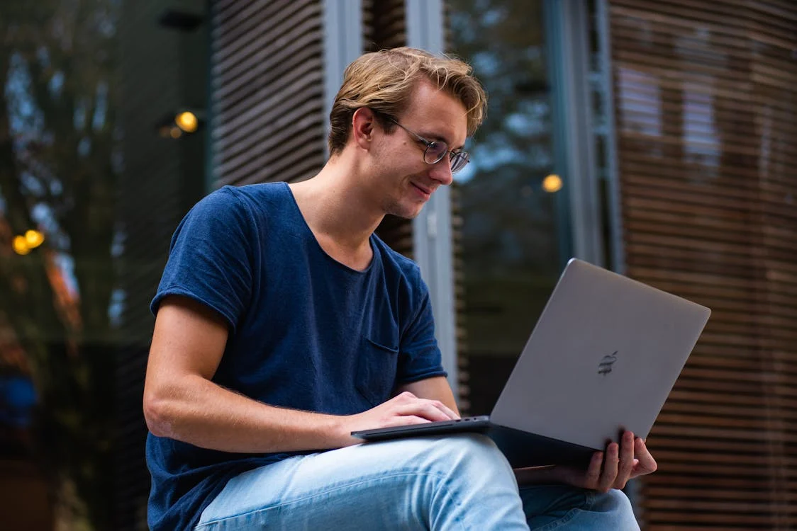 A man smiling while using a laptop