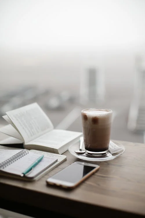 A notebook, book, smartphone, and coffee