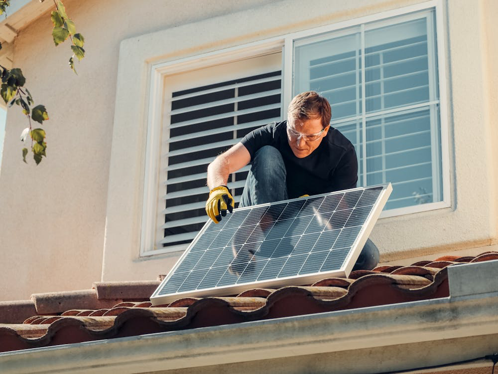 A man installing a solar panel on a home